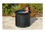 Man relaxing in an inflatable ice bath outdoors on a paved patio.