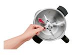 A hand removing the blade from a stainless steel blender jar with a red arrow indicating the direction.