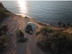 CRIVIT 4 Person Blackout Tent and a smaller tent set up on a cliff overlooking the sea at sunset.