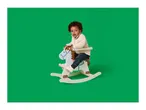 Toddler with curly hair on a white and blue rocking horse against a green background.