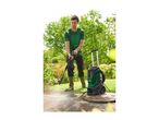 Man in a green t-shirt and boots pressure washing a patio in a garden.