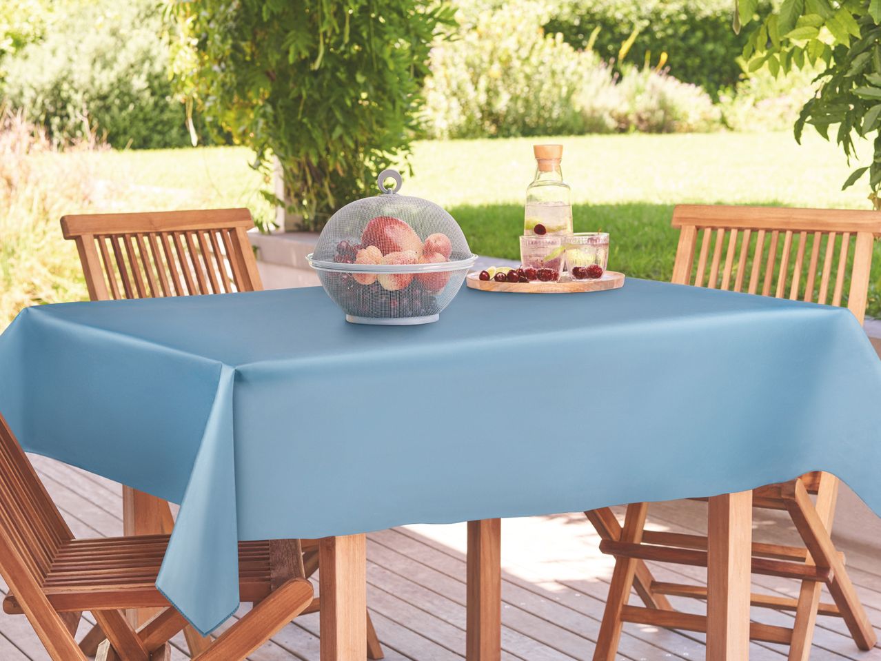 A light blue rectangular tablecloth on a wooden outdoor table with a fruit basket.