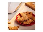 A red plate filled with animal-shaped gingerbread cookies, with more cookies scattered around.