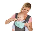 Smiling mother with baby in a gray and turquoise baby carrier.