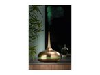 A metallic gold essential oil diffuser emitting green mist on a wooden table.