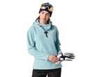 Woman in blue fleece hoodie, ski goggles, and black ski pants holding ski gloves.