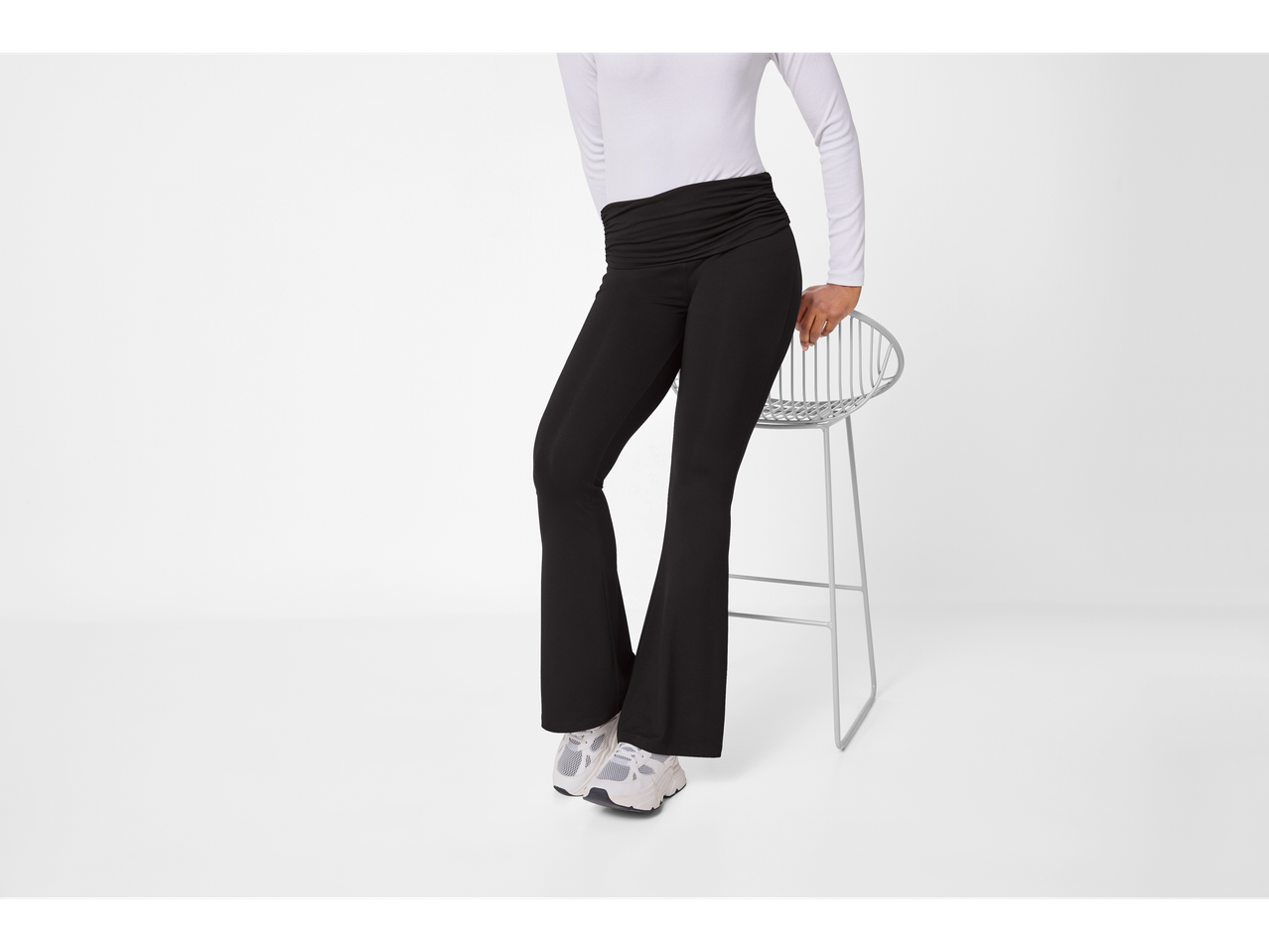 esmara® Ladies' Leggings in black, worn with a white long-sleeve top, sitting on a stool.