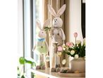 Two Easter bunny plush toys, one holding a carrot, with tulips and decorative eggs.