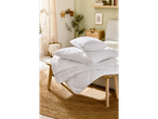 Folded duvet and pillows on a wooden side table.