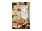 Home office with a whiteboard calendar, desk, and shelves with plants and decor.