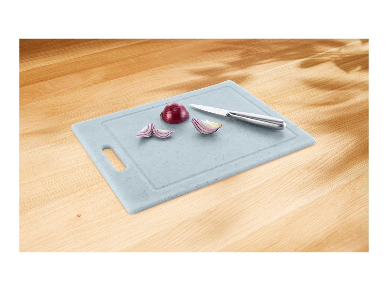 Light blue cutting board with a knife and sliced red onion on a wooden surface.