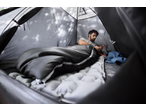 Man relaxing in a CRIVIT Camping Tent, using his phone while lying on a sleeping pad.