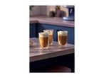 Three glasses of frothy coffee on a wooden kitchen counter with a bowl of nuts.