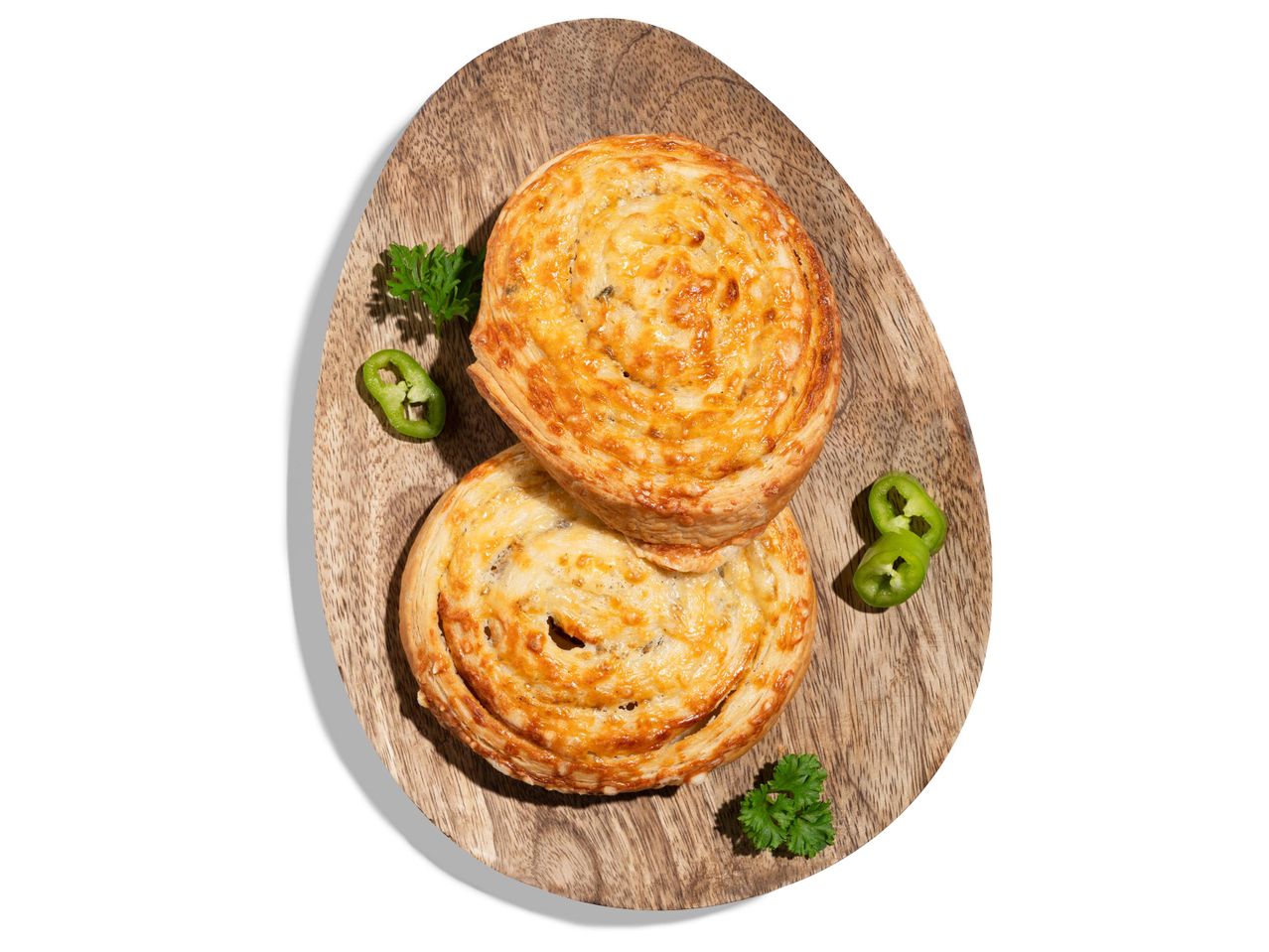Két sajtos-paprikás kifli egy fa tálcán, petrezselyemmel és jalapeno szeletekkel.
