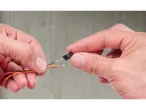 Mâini conectând trei fire la un conector negru.