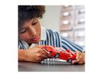 Child playing with a red toy car on a table.