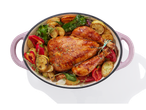 Frango assado com batatas e legumes em uma panela rosa.