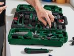 A person organizes Bosch tools in a green carrying case.