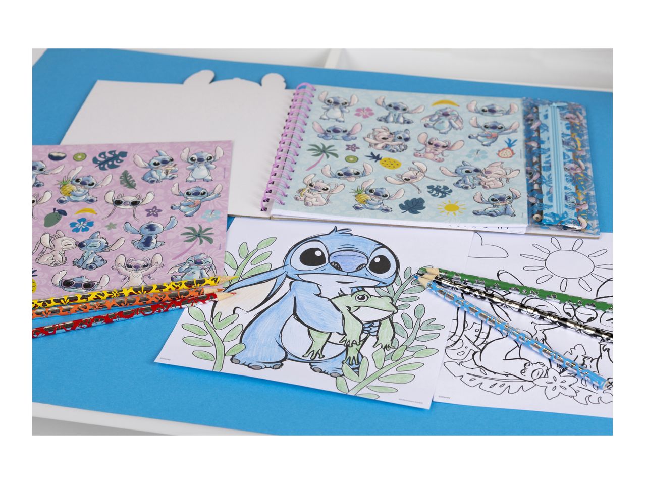 Stitch-themed stationery set with notebooks, coloring pages, and pencils on a blue background.