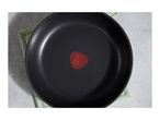 Overhead view of a black frying pan with a red heat indicator, resting on a green pot holder.