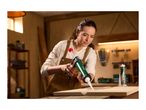 Woman applying sealant with a caulk gun to a wooden board in a workshop.