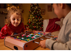 Two children playing with a Lupilu tabletop foosball game near a Christmas tree.