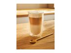 Latte macchiato in a tall glass with a golden spoon on a wooden surface.