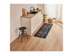 A modern kitchen with light wood flooring, white cabinets, a black sink, and a spice-themed runner rug.