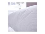 Close-up of a white textured pillow with a subtle pattern, in a bright room.