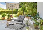 A garden swing chair with a grey cushion on a patio, surrounded by potted plants and an umbrella.