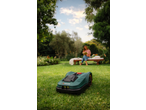 PARKSIDE® 20V Robot Lawn Mower on grass, with a woman reading in the background.