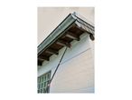 Telescopic duster cleaning cobwebs from the roof eaves of a house