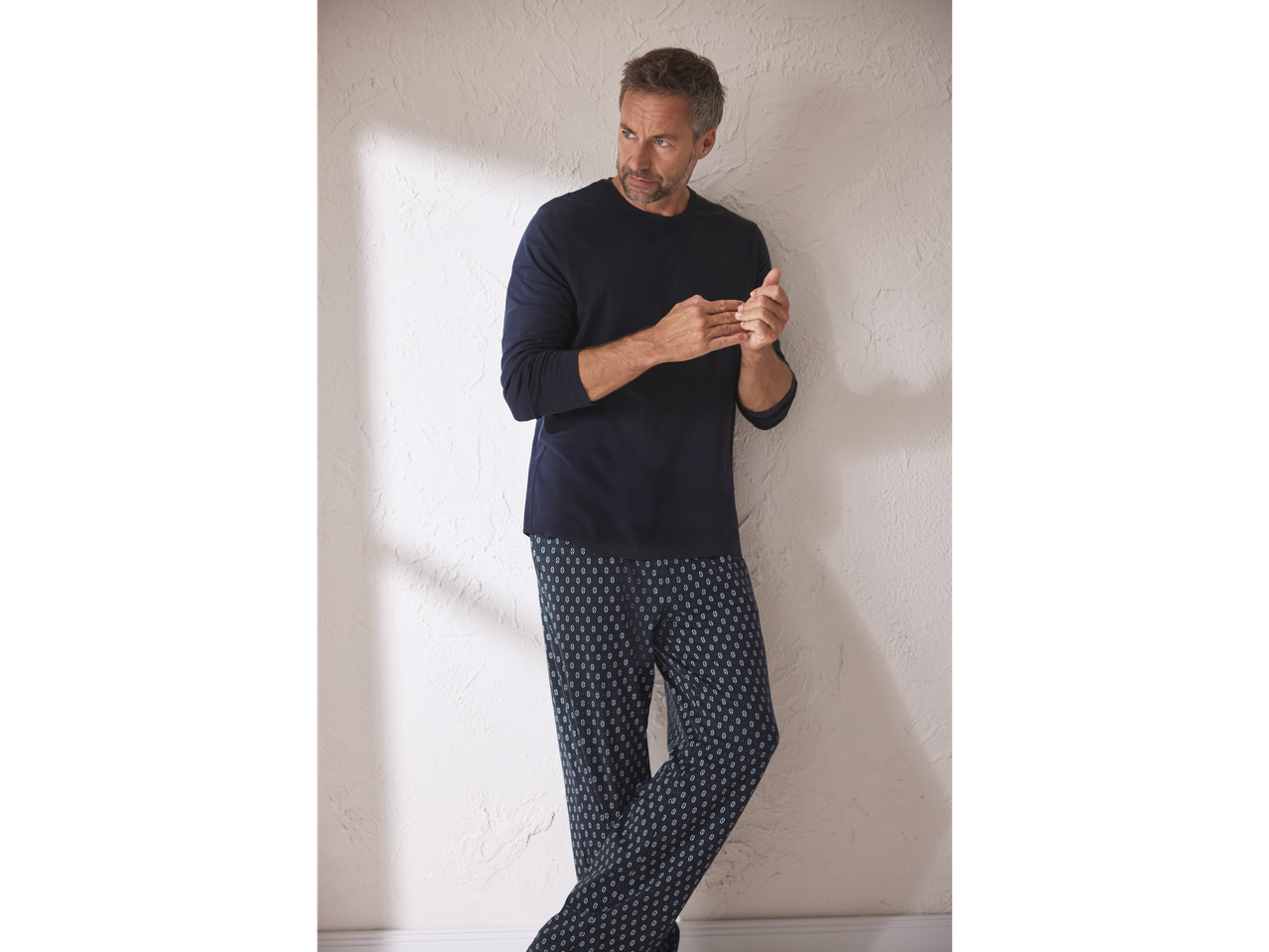 Man in donkerblauwe esmara Men® pyjama met lange mouwen en een broek met patroon.