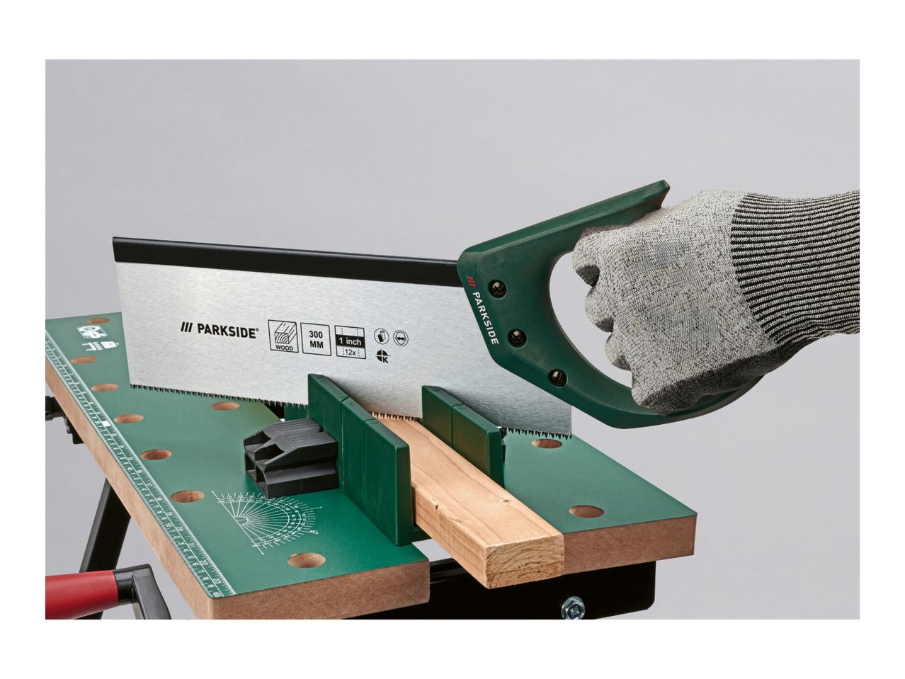 Hand saw cutting wood on a workbench with a miter box.
