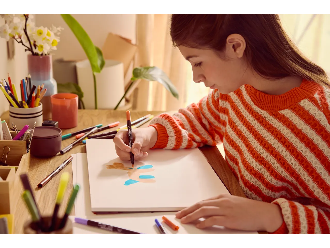Момиче рисува с акварелни маркери CRELANDO върху блок за рисуване.
