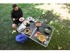 Homem a desfrutar de uma refeição ao ar livre, mesa com comida e cadeira de campismo Crivit.