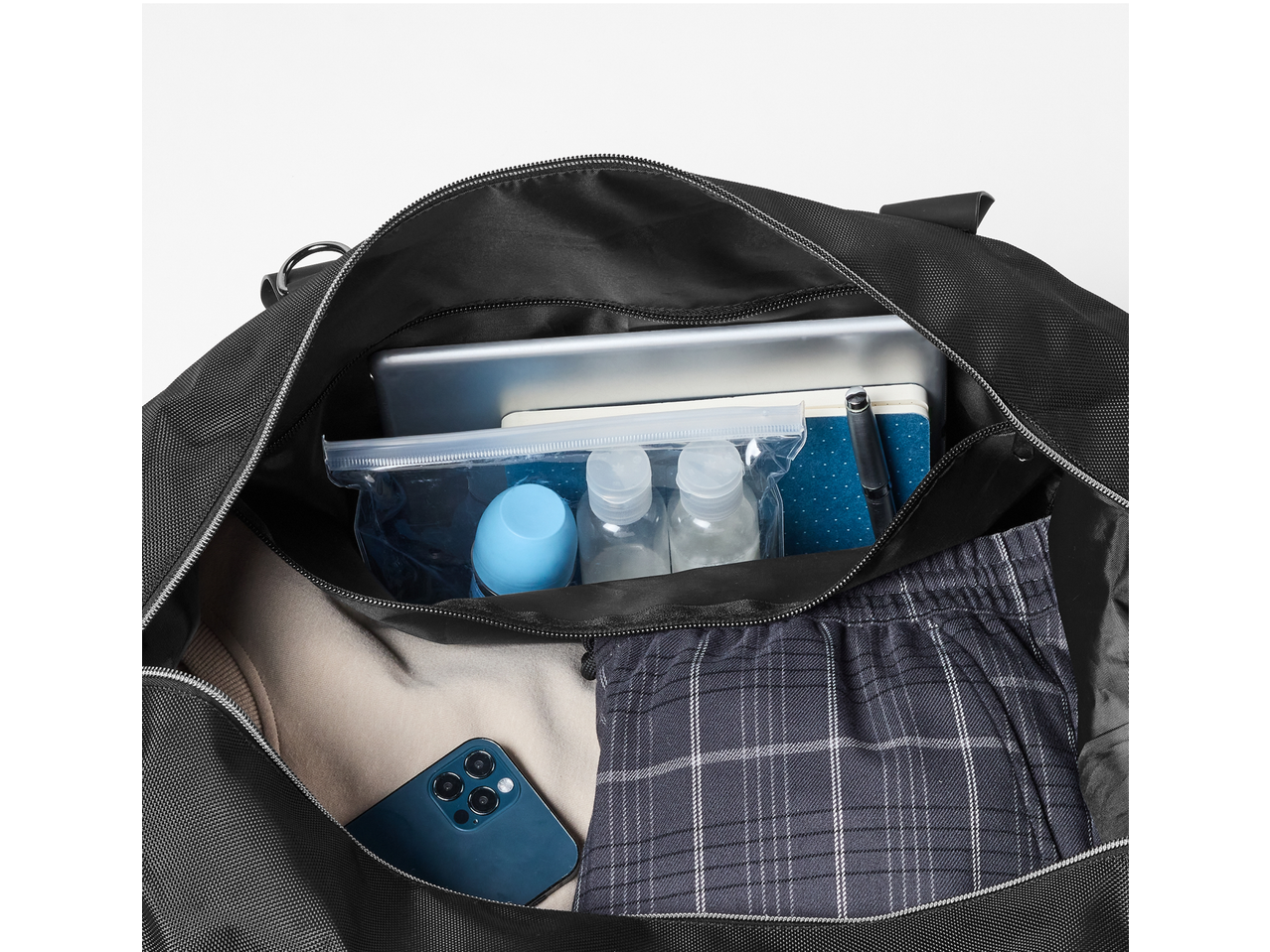 Saco desportivo ESMARA Soma aberto com tablet, caderno, caneta, frascos de viagem, calças e smartphone.