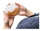 Hands holding a round, clear gel hand warmer with a brown and white design.