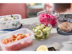 Arroz, salmão, pepinos e cebola vermelha em recipientes de comida.