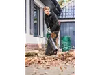 A man uses a Bosch leaf blower to clear autumn leaves from a patio.
