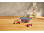 Gray plastic food container with raspberries and blueberries.