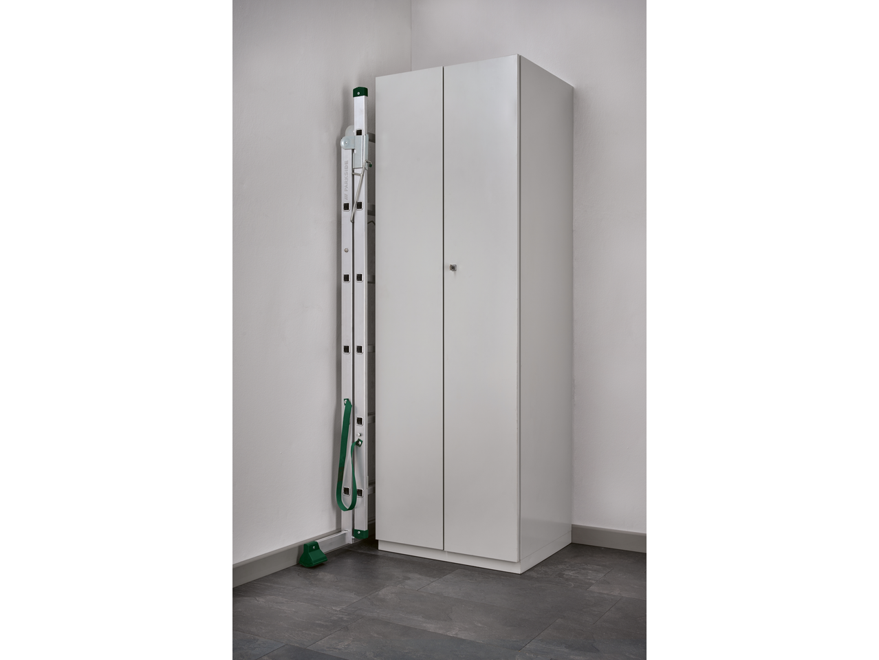 A white storage cabinet and a folded ladder with green accents in a corner.