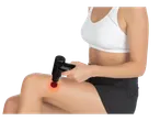 Woman using a VITALMAXX® mini massage gun with red light therapy on her leg.