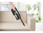 Aspirador de mão Silvercrest® 2 em 1 a limpar migalhas de um sofá bege.