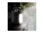 Portable work light on a wooden table in a garden setting.