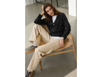 Woman in esmara® Ladies' Chunky Knit Cardigan, white tee, beige pants, and leopard print shoes.