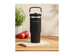 A black Silvercrest travel mug on a wooden board with apples and a plant.