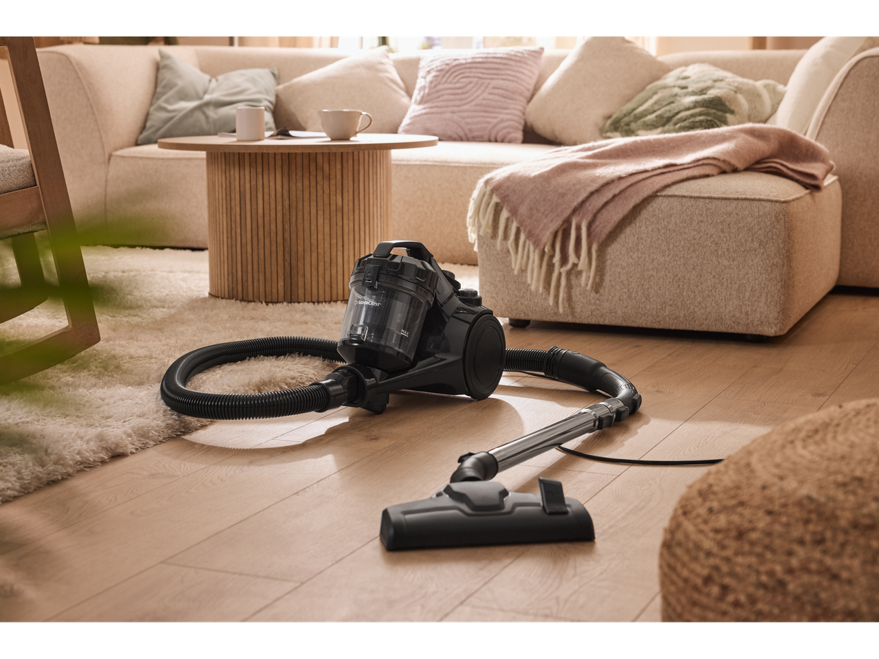 Aspirador Silvercrest® numa sala de estar com tapete claro e sofá.