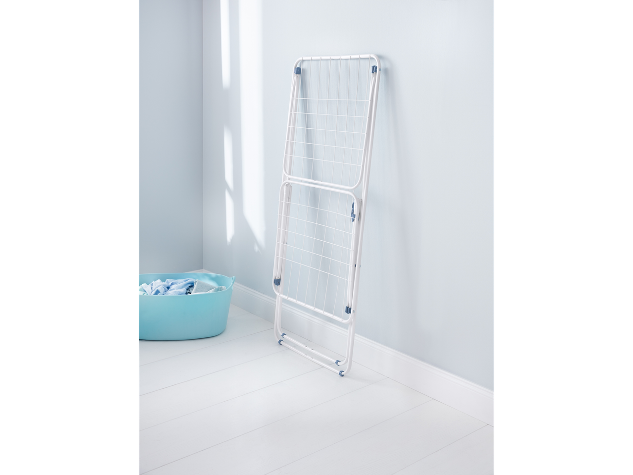 A white drying rack and a blue laundry basket in a room.