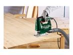 Person using a green jigsaw with a dust extraction hose to cut a wooden board.